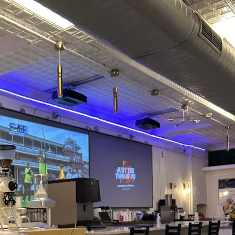 Interior of Botbar Vegan Cafe with blue LED lights, projectors, and bar seating.